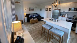 A compact kitchen with a central island, a dining area with a table and chairs, and a living room with a sofa.