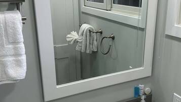A bathroom with a large mirror, a sink, and a towel rack.