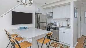 A compact kitchen with white cabinets, stainless steel appliances, and a dining area with a table and chairs.
