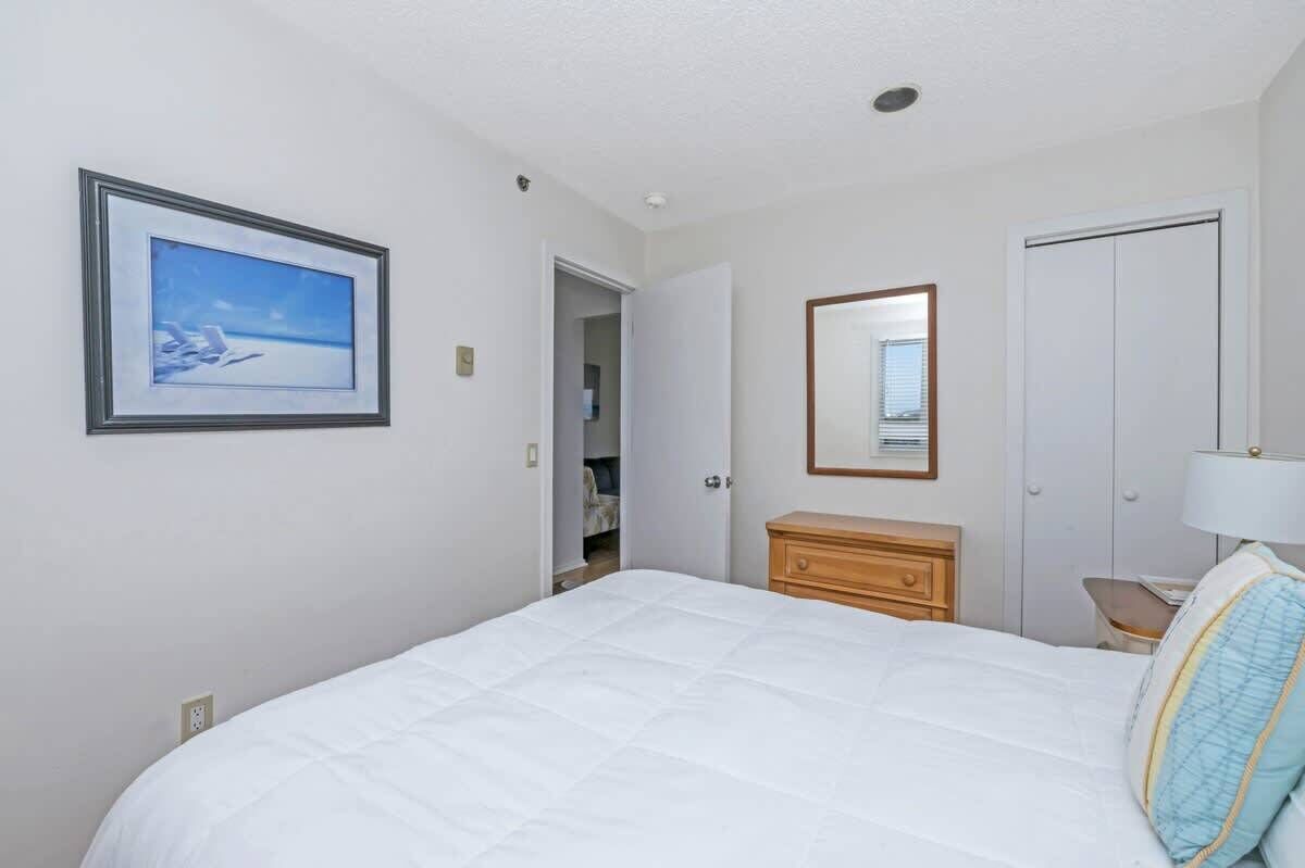 A bedroom with a bed, a dresser, a mirror, and a framed picture on the wall.
