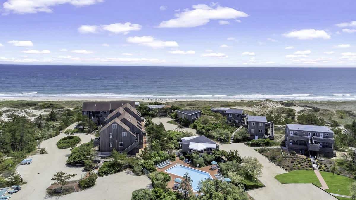 Un hotel frente al mar con varias construcciones, piscina y vistas a la playa.
