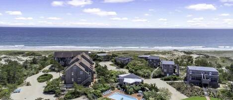 Un hotel frente al mar con varias construcciones, piscina y vistas a la playa.