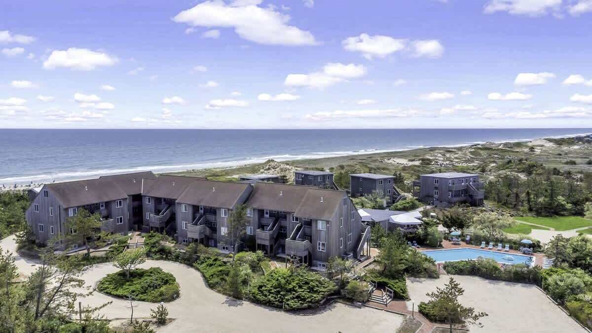 A coastal hotel with multiple buildings, a swimming pool, and a view of the ocean.
