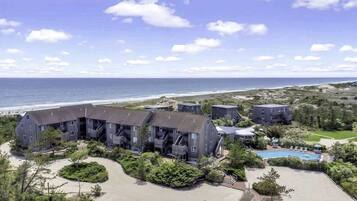 A coastal hotel with multiple buildings, a swimming pool, and a view of the ocean.