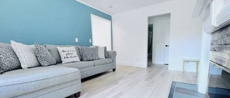 Un salon moderne avec un canapé gris, des coussins à motifs et un mur d’accent bleu.