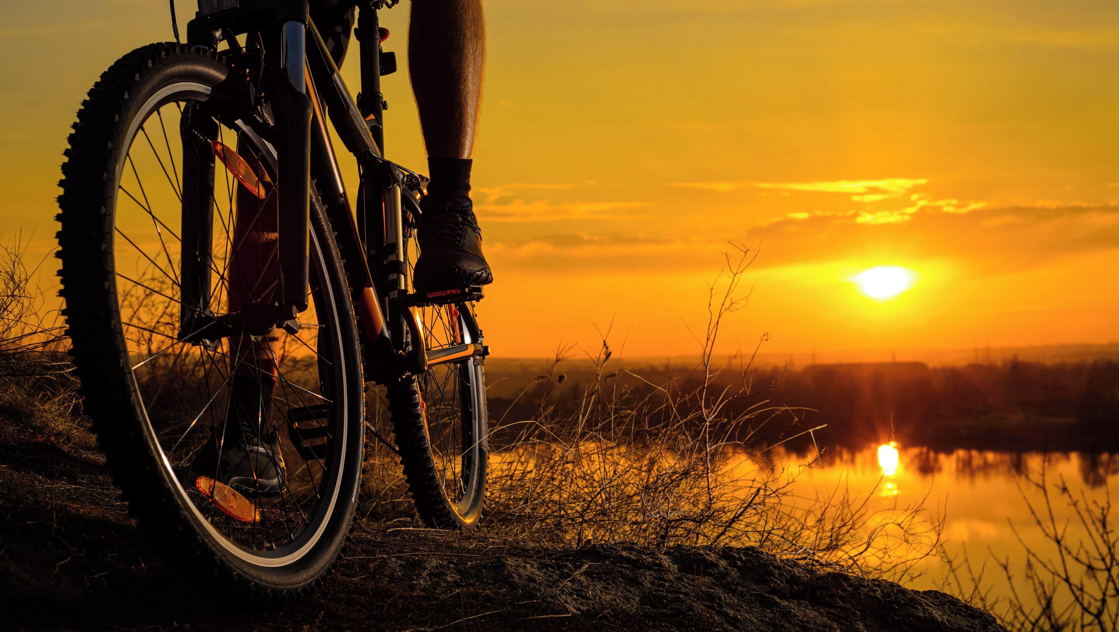 Una bicicleta de montaña sobre terreno rocoso con un atardecer de fondo.
