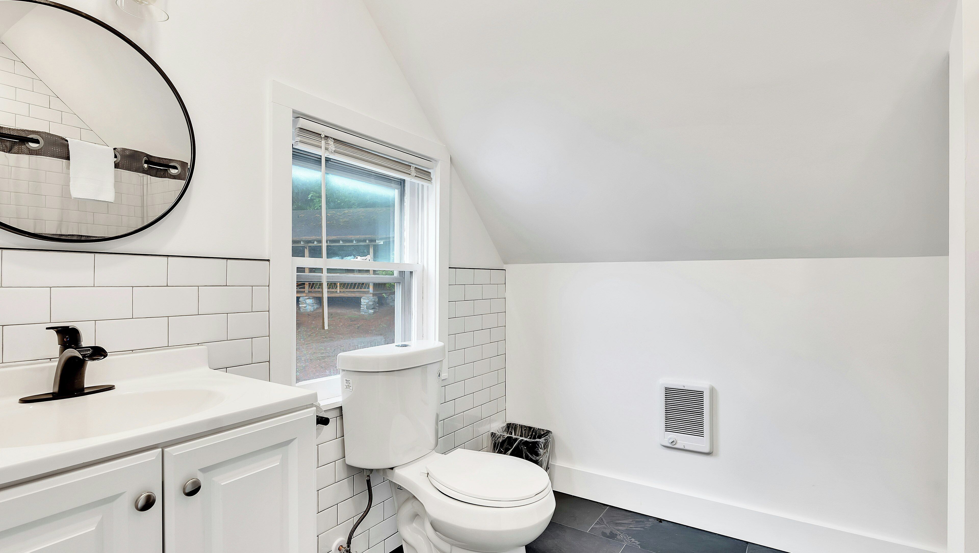 A white bathroom with a toilet, sink, and window.