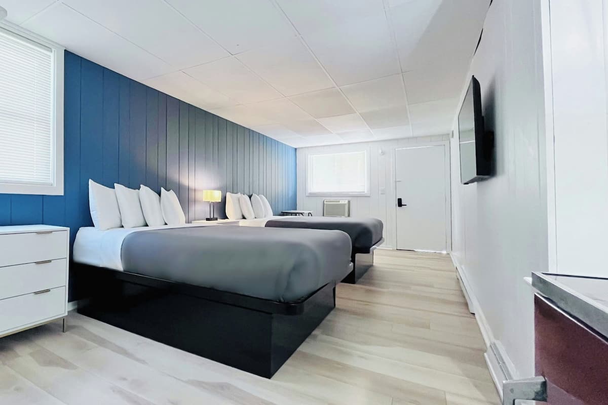 A modern hotel room with a large bed, a bedside table, a desk, and a TV mounted on the wall.