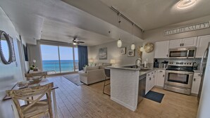 Una cocina moderna con armarios blancos, una isla central y vista al océano.