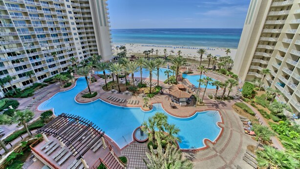 Un hotel con piscina, vista al mar y palmeras.