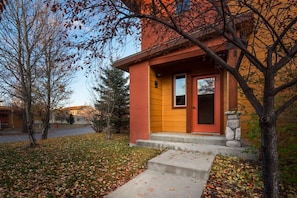 A two-story house with a red door and a small porch. - Mountain Laurel Condo: Porch Views, AC, Close to Music on Main (Victor)