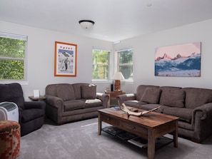 A living room with two sofas, a coffee table, a heater, and framed artwork on the walls. - Mountain Laurel Condo: Porch Views, AC, Close to Music on Main (Victor)