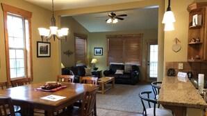 A spacious living room with a dining area, a kitchen with a granite countertop, and a ceiling fan. - Second Level Condo - BJ#6 (Driggs)
