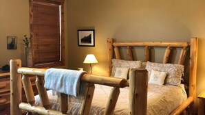 A rustic wooden bed frame with a headboard, a ceiling fan, and a lamp on a bedside table. - Second Level Condo - BJ#6 (Driggs)
