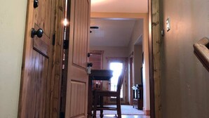 A hallway with wooden doors, a carpeted floor, and a view into a room with a chair and a table. - Second Level Condo - BJ#6 (Driggs)