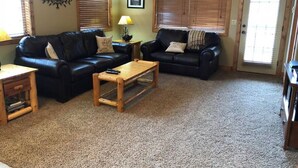 A living room with two black leather sofas, a wooden coffee table, and a small wooden side table. - Second Level Condo - BJ#6 (Driggs)