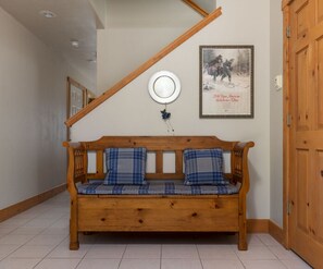A wooden bench with plaid cushions in a hallway with a wooden door and a framed picture on the wall. - Cozy 2 level townhome with scenic views - SR # 47 (Driggs)
