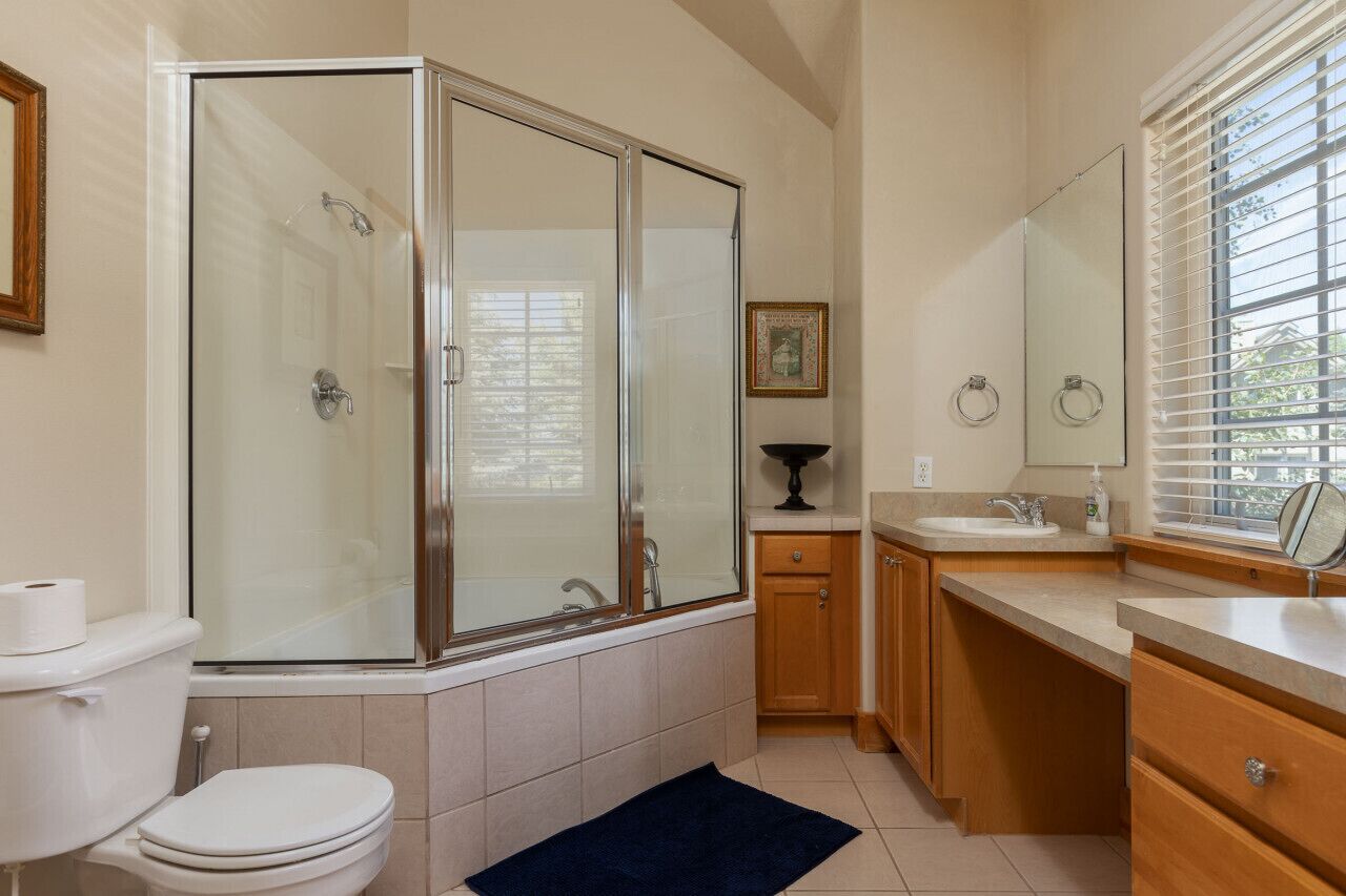 Un baño con ducha envuelta en cristal, inodoro, lavabo y espejo.