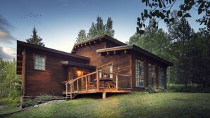 A wooden cabin with a deck and large windows, surrounded by trees. - Windigo Lodge with Hot Tub (Victor)