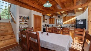 A wooden interior with a dining table, chairs, a kitchen area, and a staircase. - Windigo Lodge with Hot Tub (Victor)