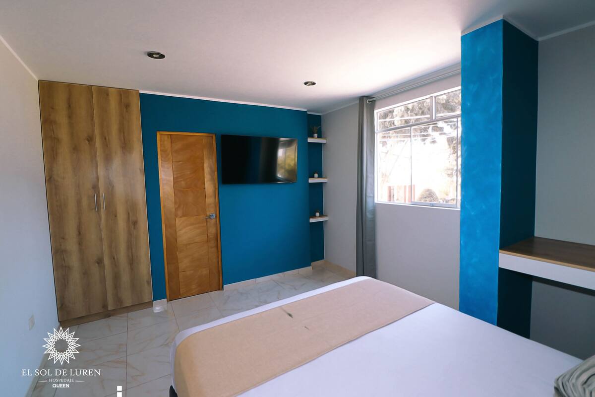 Une chambre à coucher avec un lit, une armoire, une télévision et une fenêtre donnant sur un beau paysage.