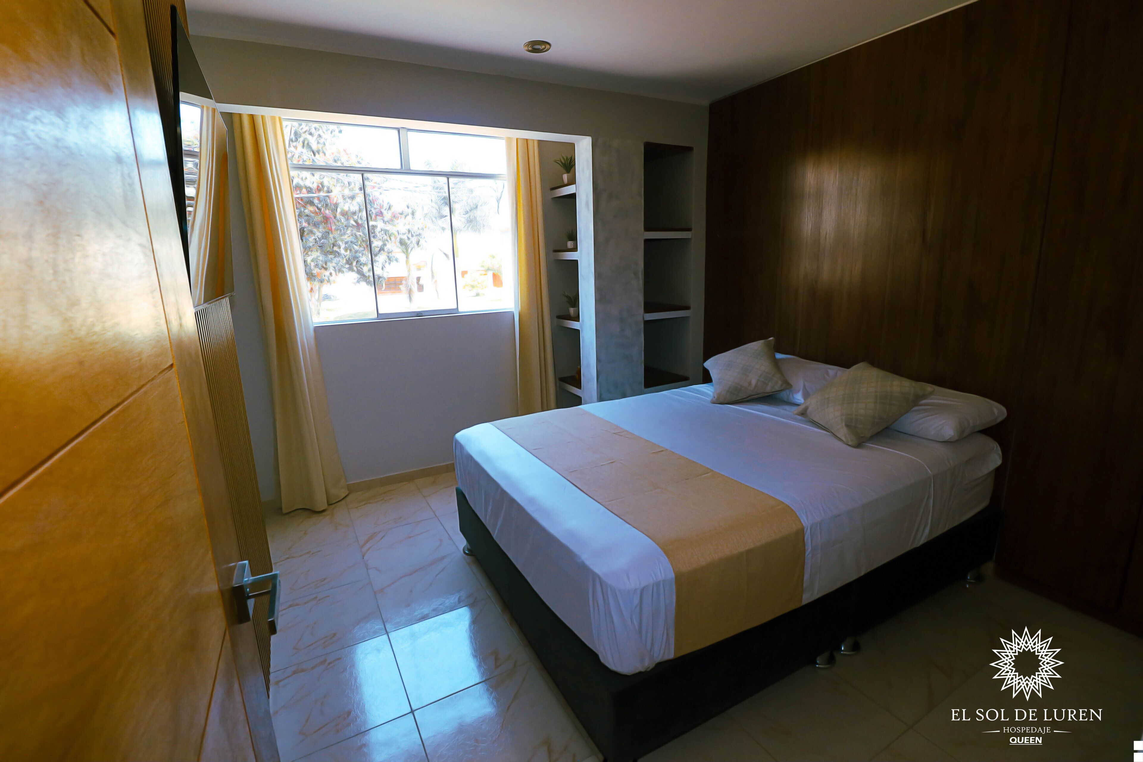 Un dormitorio con una cama, una ventana con cortinas y una pared de madera.
