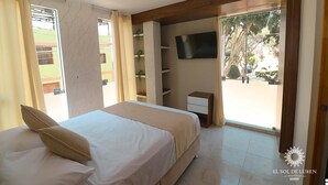 A hotel room with a bed, a TV mounted on the wall, a small desk, and a balcony with a view of the outside. - SOL DE LUREN PUENTE BLANCO (Ica)