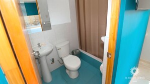 A bathroom with a toilet, sink, and shower curtain. - SOL DE LUREN PUENTE BLANCO (Ica)