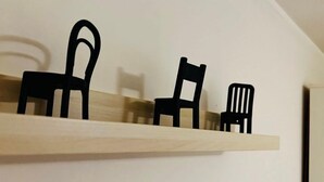 A wooden shelf with three black chair silhouettes against a plain wall. - Sweet Home - 101 (Catania)