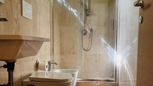 Une salle de bain avec douche, toilettes et lavabo.