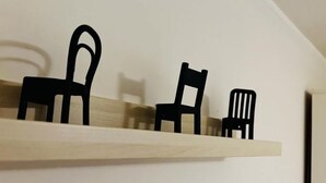 Une étagère en bois, avec trois chaises noires de styles différents, placée contre un mur uni.