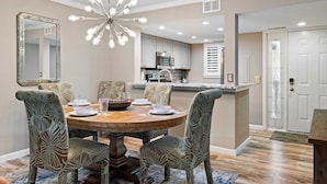 A dining area with a round wooden table, patterned chairs, and a modern chandelier. - Beautiful Spacious Condo w/Pool walk to Beach, Celebration Park, Coligny Plaza! (Hilton Head Island)