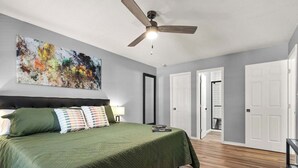 A bedroom with a bed, a ceiling fan, a painting, and a door leading to another room. - 2 bed/ 2 bath condo * Balcony * King Bed (Pensacola)