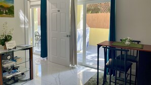 Ein Hotelzimmer mit Glastür zu einem Balkon, einem Schreibtisch mit Stuhl und einem kleinen Tisch mit Blumenvase.