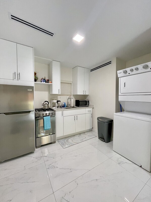 A modern kitchen with white cabinets, stainless steel appliances, a microwave, and a built-in oven.