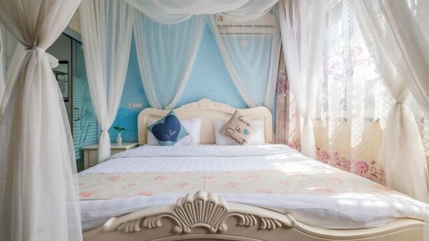 A bedroom with a bed, curtains, and a nightstand.