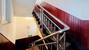 A staircase with metal railings, wooden walls, and a light fixture.