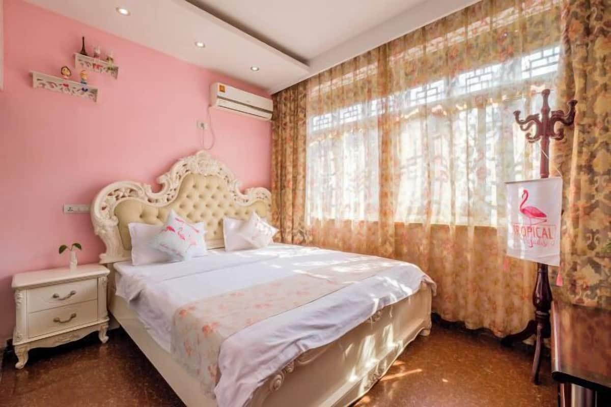 Un dormitori amb un llit gran, una tauleta de nit, una paret decorativa i una finestra amb cortines.
