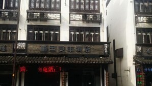 A hotel facade with traditional Chinese architectural elements, including wooden lattice windows and a tiled roof.