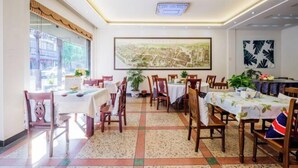 A dining area with multiple tables and chairs, a large map on the wall, and potted plants.