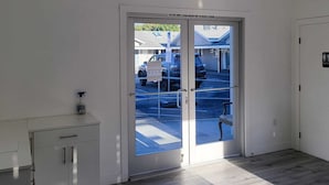 A hotel entrance with a glass door, an exit sign above, and a small cabinet to the left. - Stafford Inn (Redwood City)