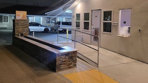 A hotel entrance with a stone bench, a ramp, and a handrail. - Stafford Inn (Redwood City)