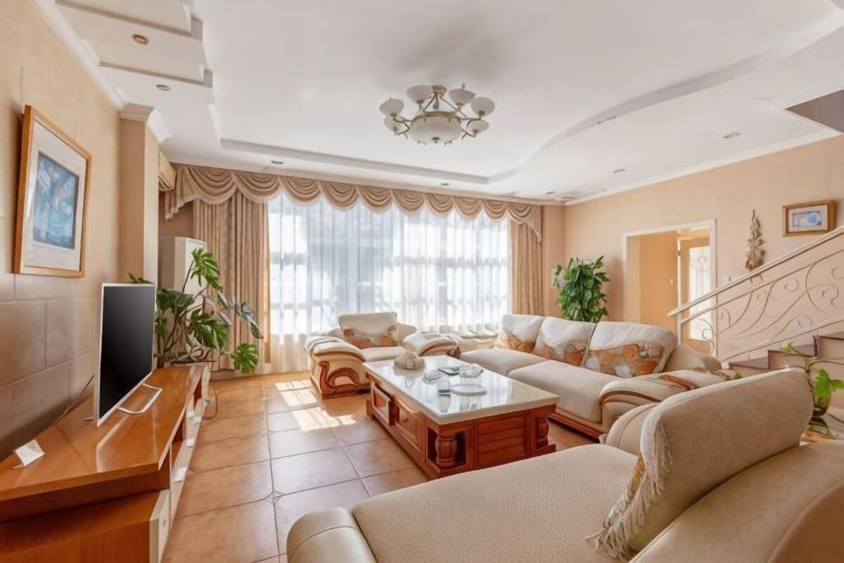 A spacious living room with a sofa set, a coffee table, a TV, and a staircase.