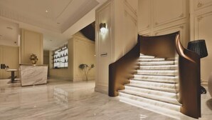 A grand staircase with a unique design, leading to a well-lit area with a reception desk and a vase of flowers. - Yuequ Dianchi Lake Chinese Inn (Kunming)