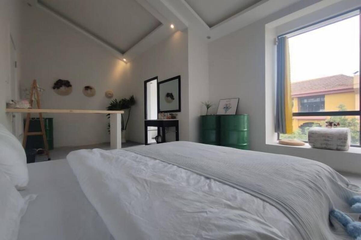 A bedroom with a bed, a desk, a window with a view, and a green cabinet.