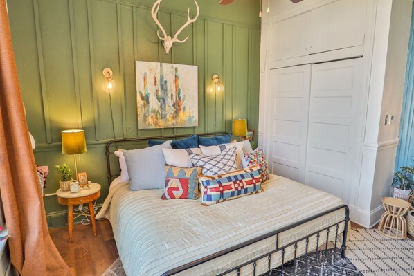 Une chambre à coucher avec un lit, deux lampes de chevet, un tableau accroché au mur et une porte.