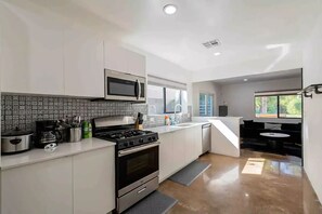 A modern kitchen with white cabinets, a stainless steel stove, and a microwave.