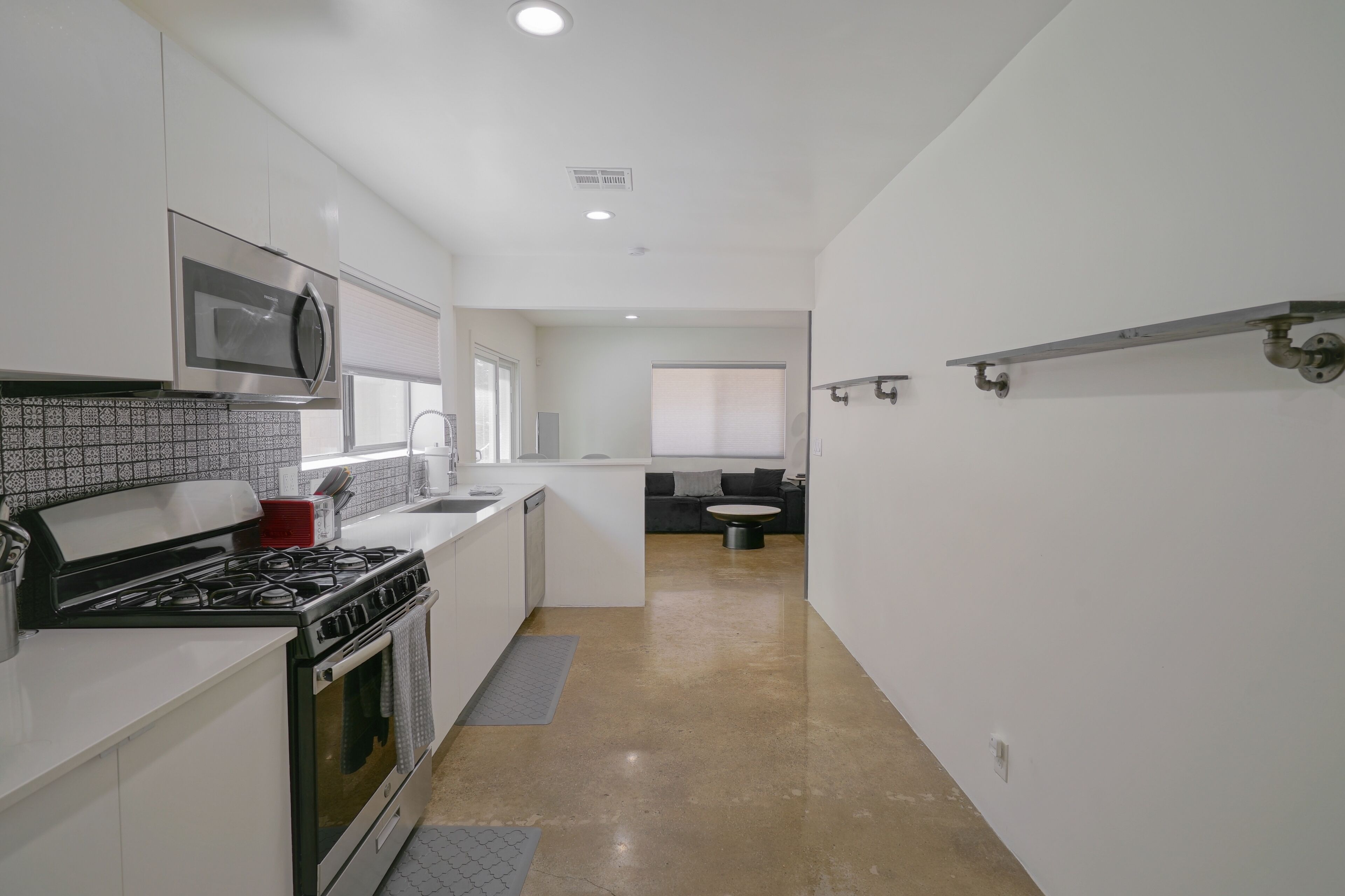 A modern kitchen with white cabinets, a stainless steel microwave, and a gas stove.