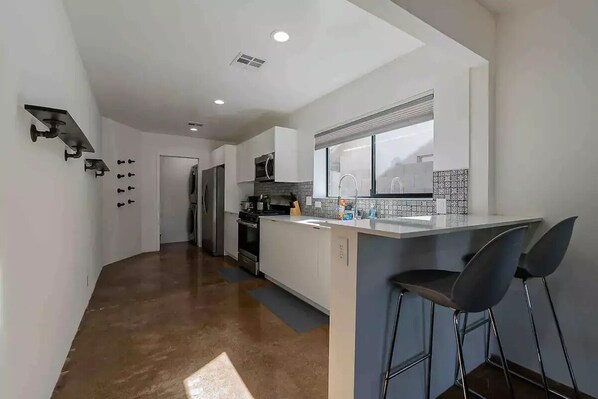 A modern kitchen with white cabinets, a stainless steel refrigerator, and a window above the sink.