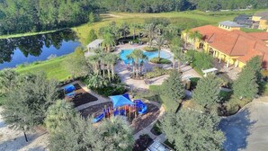 Vista aérea de um resort com piscina, parquinho e vegetação ao redor.